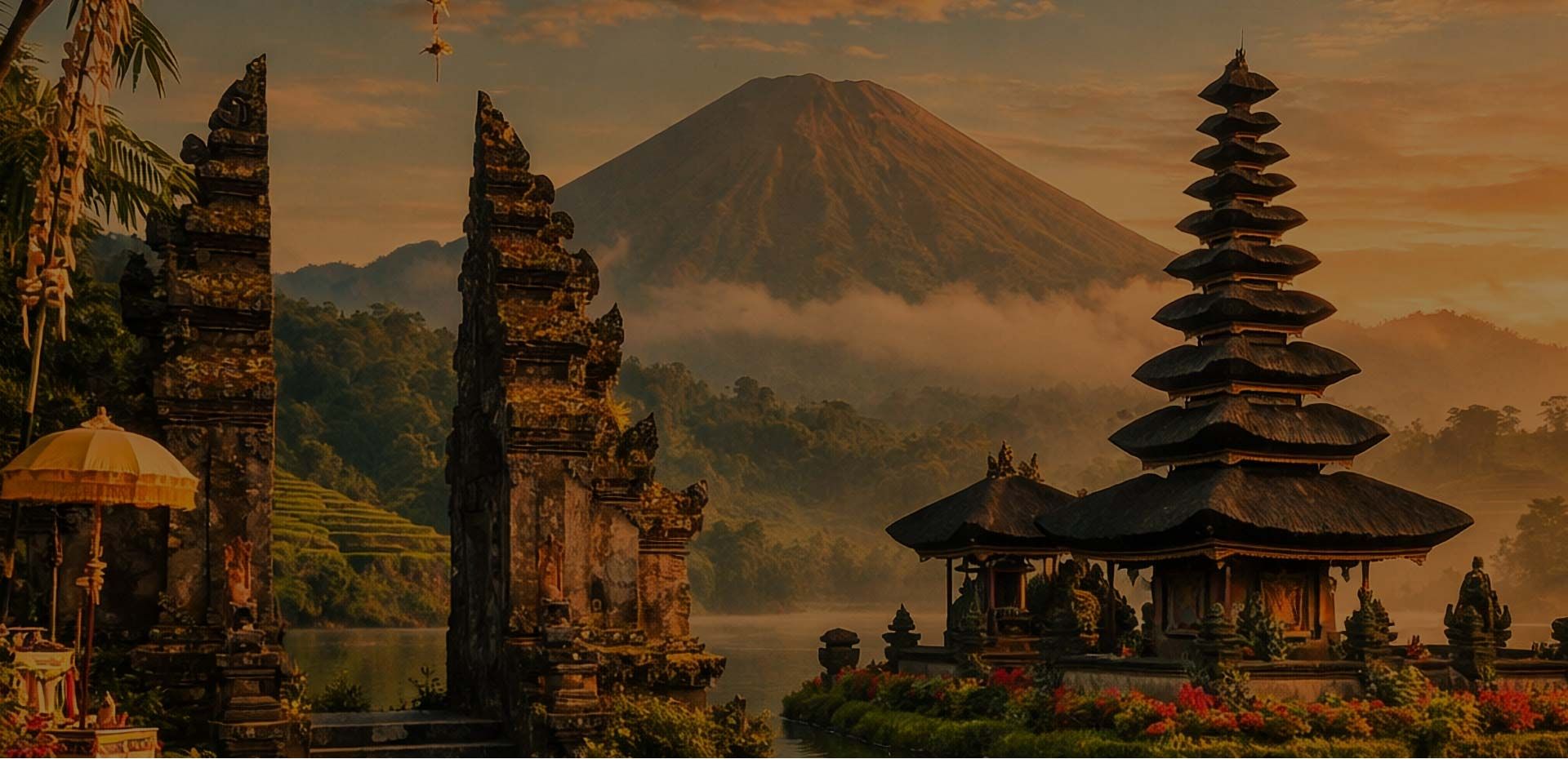 Balinese temple gates and pagoda with mountain backdrop at sunset